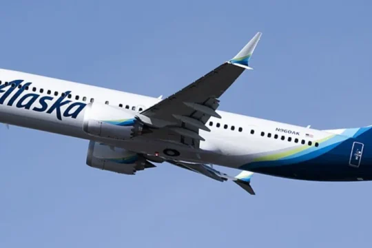 An Alaska Airlines plane with blue tail and white fuselage takes off.