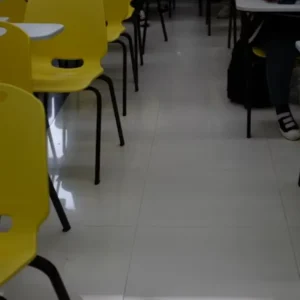 Rows of empty yellow and white chairs and desks in a classroom.