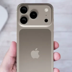 A hand holds a gold iPhone with multiple cameras, Apple logo visible.