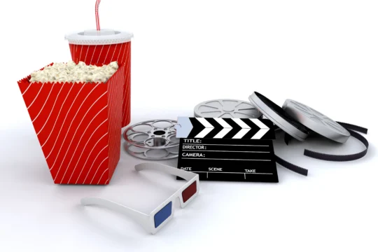 Assorted movie elements including popcorn, soda, film reels, clapperboard, and 3D glasses on a white background.