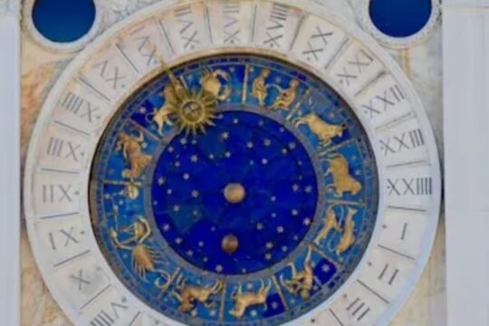 Zodiac astronomical clock with golden astrology symbols on a blue celestial background, surrounded by Roman numerals.