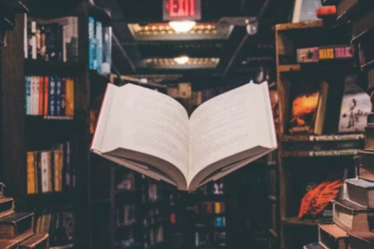 Open book floating in a dimly lit library aisle