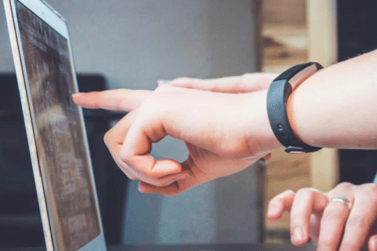 Hands pointing at a laptop screen during discussion