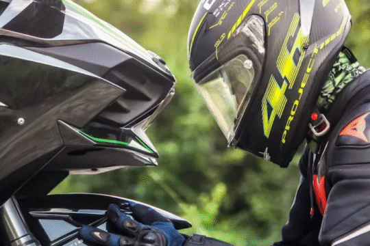 A motorcyclist in black riding gear and a helmet labeled "46 Project" leans closely towards a high-performance Sport Bike, both facing each other.