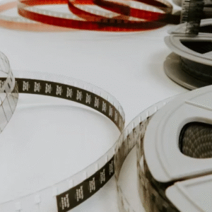 Close-up view of vintage film reels and unwound filmstrips laid out on a white surface.