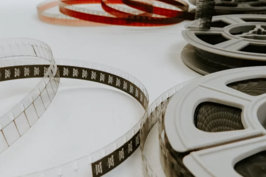 Close-up view of vintage film reels and unwound filmstrips laid out on a white surface.