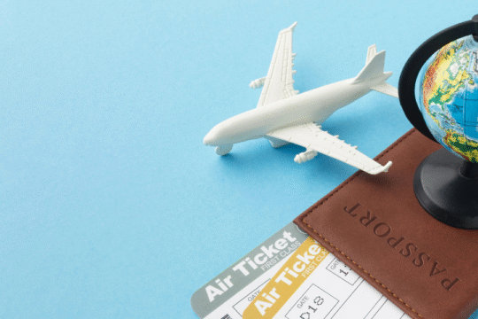Miniature airplane, globe, passport, and air tickets arranged on a blue background, symbolizing international travel and visa processing.