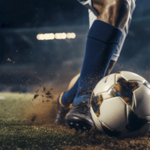 Close-up of a football player kicking a soccer ball on a stadium field under floodlights