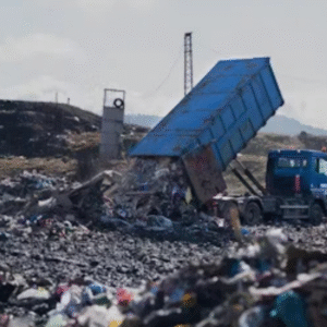 Truck unloading garbage at a large landfill site.
