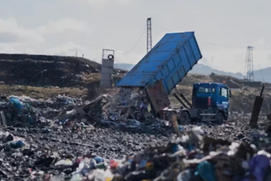 Truck unloading garbage at a large landfill site.