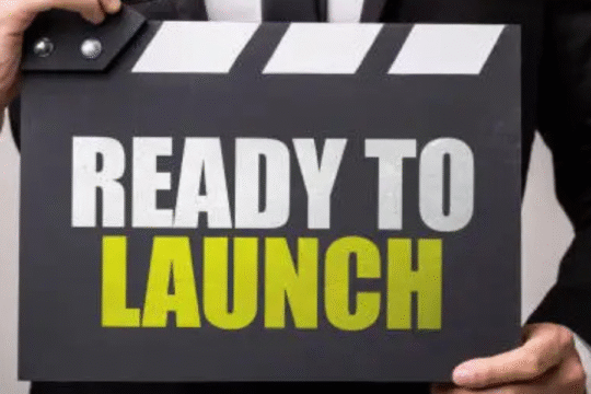Person holding a clapperboard-style sign saying "Ready to Launch"