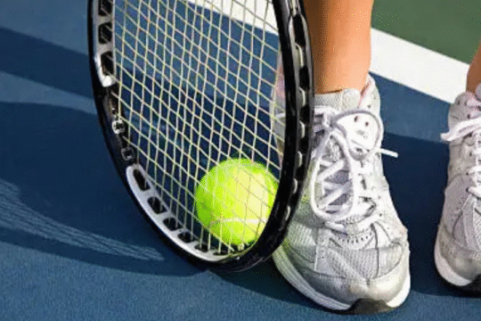Tennis racket and ball near player’s feet
