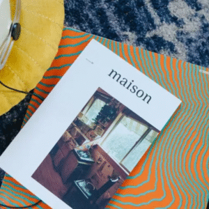 Overhead view of a vinyl record, headphones, and a "maison" magazine on a colorful surface.