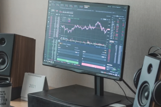 Computer screen displaying cryptocurrency trading chart on a modern desk setup.