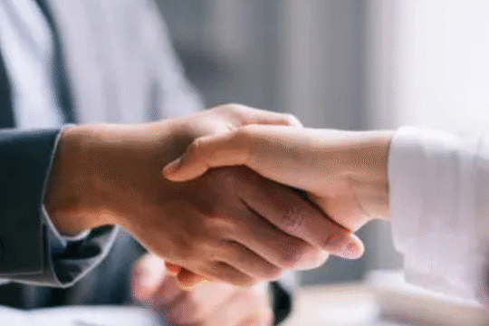 Close-up of a business handshake between two professionals in formal attire, symbolizing partnership or agreement.