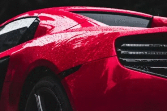 Sleek red sports car with rain droplets on its surface