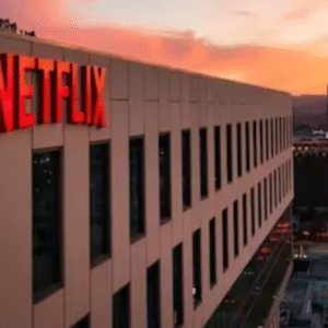 Netflix headquarters building lit up at sunset overlooking a busy city street.