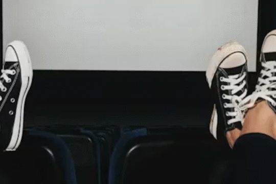 Two people with sneakers relaxing in an empty movie theater.