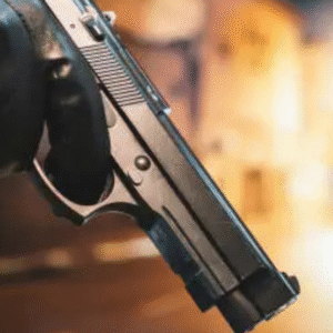 Close-up of a person holding a handgun with gloves in a dimly lit urban alley.