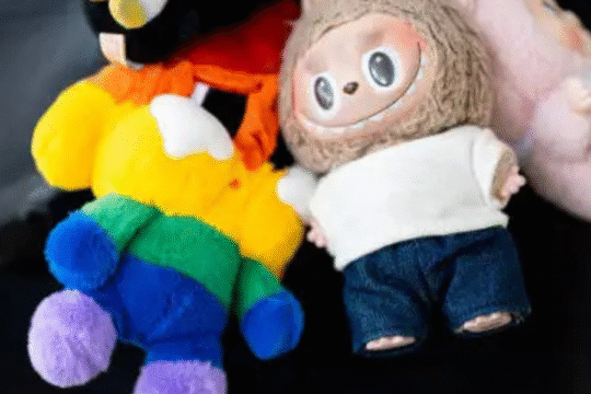 A close-up of colorful stuffed dolls, including a faux Labubu doll, hanging from a black handbag.