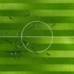 Aerial view of a green football field with players during a match.