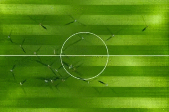 Aerial view of a green football field with players during a match.
