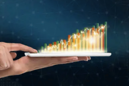 Hand holding a tablet displaying colorful 3D bar graph rising upwards
