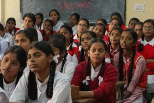 A group of Indian schoolgirls in uniform attentively listening during a classroom session.
