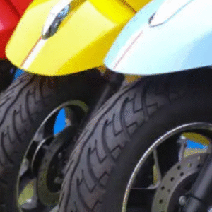 Close-up view of colorful scooters lined up with visible front tires and fenders.