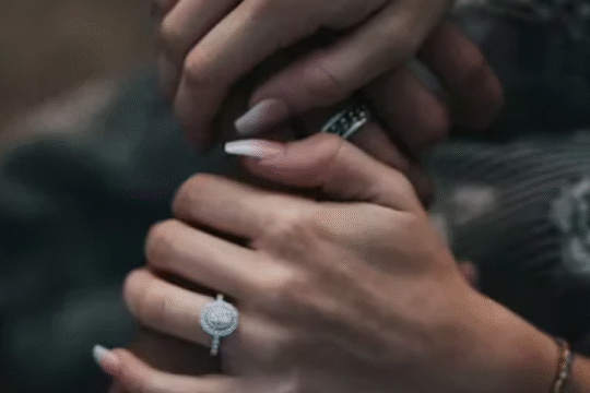 Close-up of couple holding hands showing diamond engagement rings.