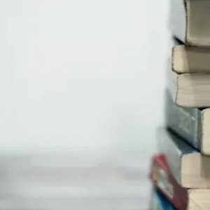 Stack of old, slightly worn books piled vertically against a plain white background.