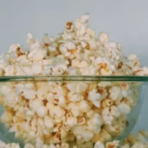 Bowl overflowing with fresh popcorn on a clean white background