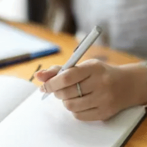Close-up of a student writing in a notebook with a pen