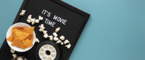 A plate of popcorn and some reels on it and it's time for movie