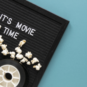 A plate of popcorn and some reels on it and it's time for movie