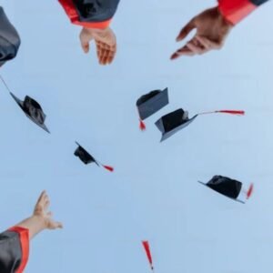 Graduates in black and red gowns celebrating by tossing caps into the sky.