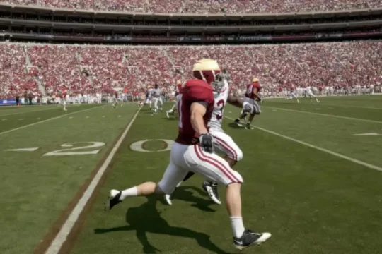 A football game with players on a field and a crowded stadium.