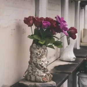 Flowers in a vase are placed on a ledge of a crypt in a cemetery.