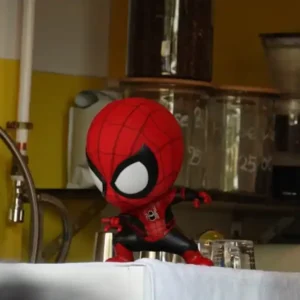 A cute, cartoon-style Spider-Man figurine sits in a window.