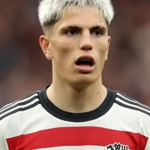 Young football player with bleached hair in a Manchester United jersey.