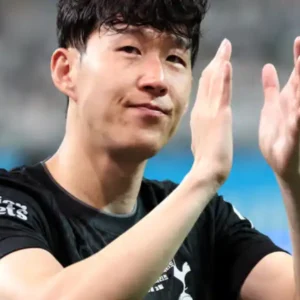 South Korean footballer Son Heung-min clapping in a stadium.