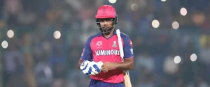 Indian cricketer Sanju Samson in a pink and blue Rajasthan Royals jersey, holding a bat.