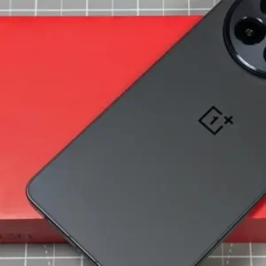 A black OnePlus 13R smartphone is placed on top of its red box.